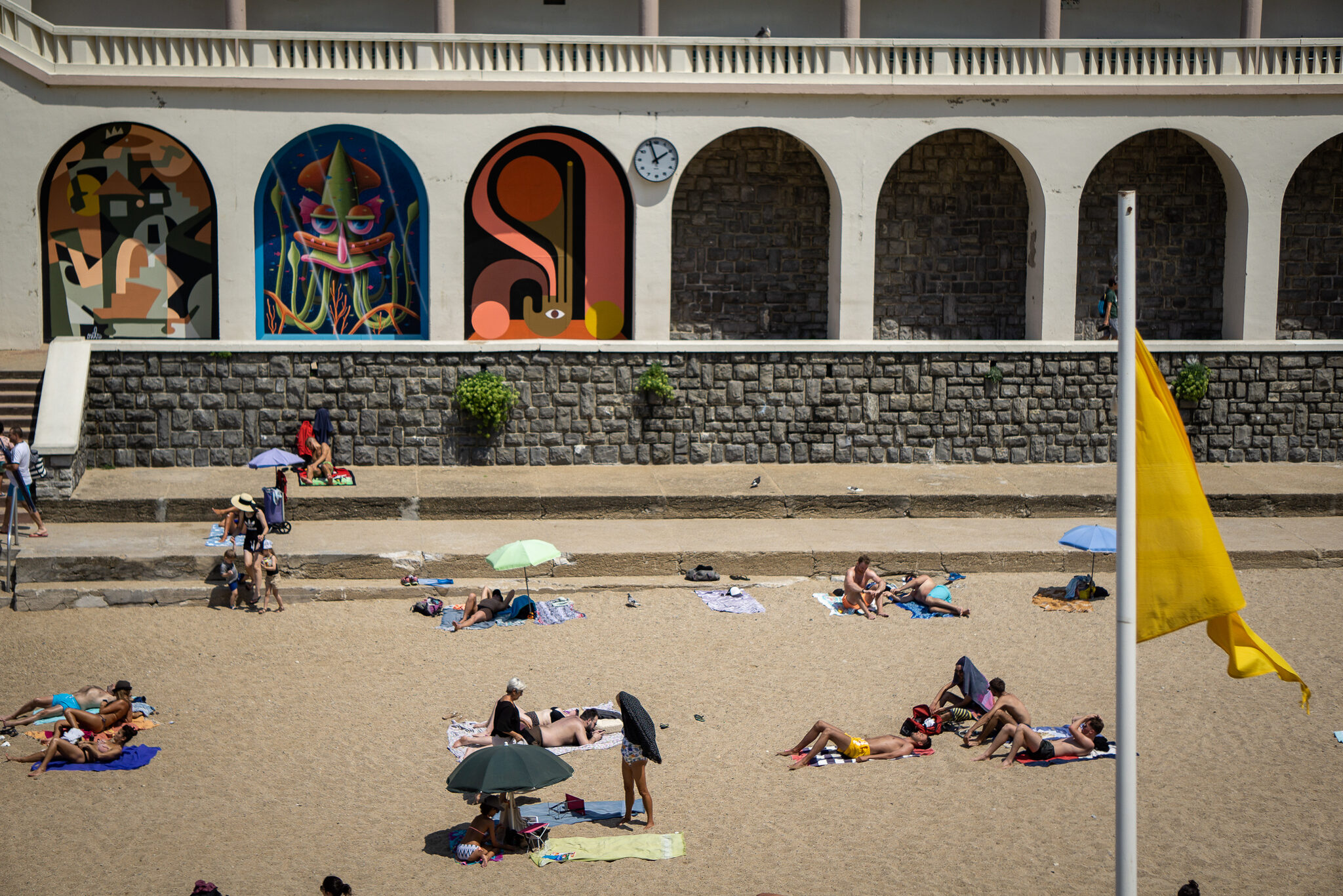 Playa bajo arquería decorada, bandera amarilla